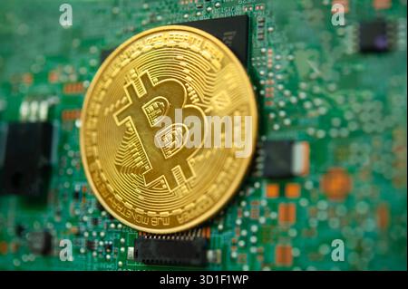 Golden Bitcoin coin on computer motherboard symbolizing cryptocurrency and digital finance Stock Photo
