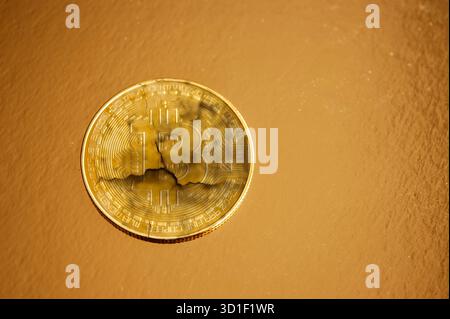 Cracked golden Bitcoin coin symbolizing cryptocurrency collapse, risk, and instability Stock Photo