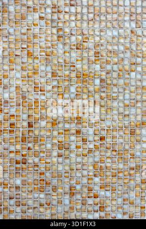 Small mosaic tiles in earthy tones forming a geometric and textured wall pattern Stock Photo