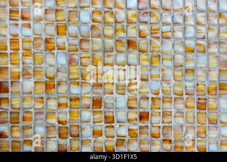 Small mosaic tiles in earthy tones forming a geometric and textured wall pattern Stock Photo