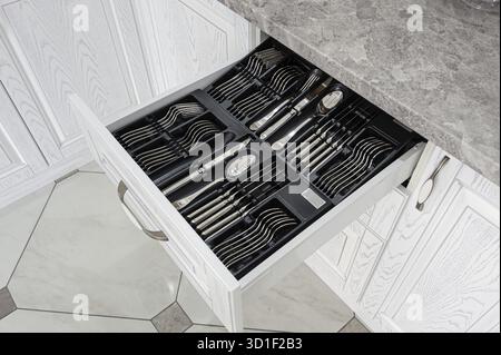 Black open drawer with silver cutlery in modern white kitchen Stock Photo