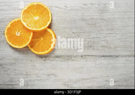 Three slices of fresh oranges on white wood background, Top view, lot of copyspace Stock Photo