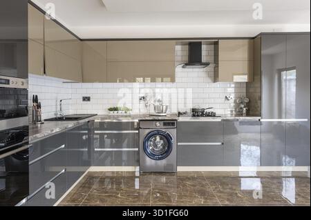 Spacious luxury well designed modern grey, beige and white kitchen with marble tiles floor Stock Photo