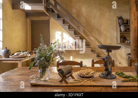 A detail of the historic kitchen of George Sand's country estate shows a wooden table with a bouquet of flowers, an antique black scale and other rust Stock Photo