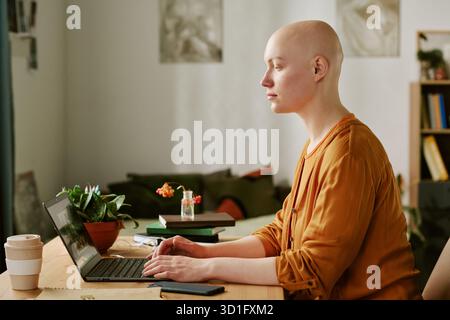 Young Adult Woman with Alopecia Using Laptop While Working Indoors Stock Photo