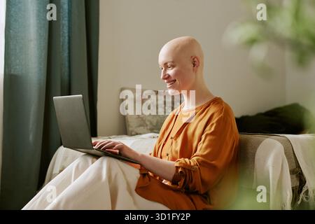 Young Adult Woman with Alopecia Using Laptop and Smiling Indoors Stock Photo