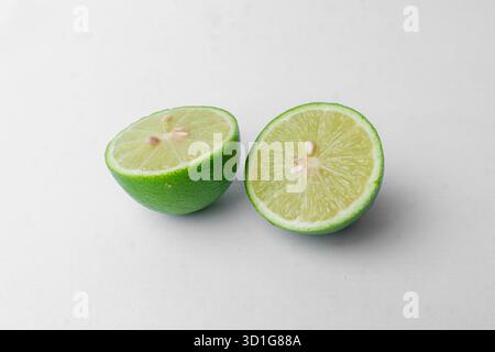 A fresh green lime cut in two halves. Isolated on a clean white studio background. Healthy citrus fruit. Minimalist with copy space. Stock Photo