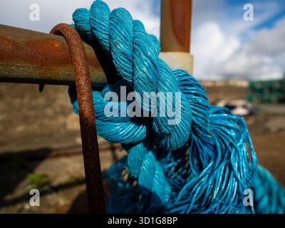 Close up of blue rope tied around a rusty metal bar Stock Photo