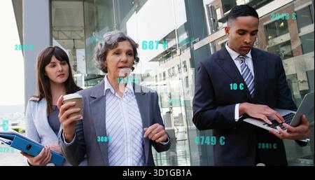 Walking team in suits discussing plan outside glass building with coffee cup blue binder laptop Stock Photo