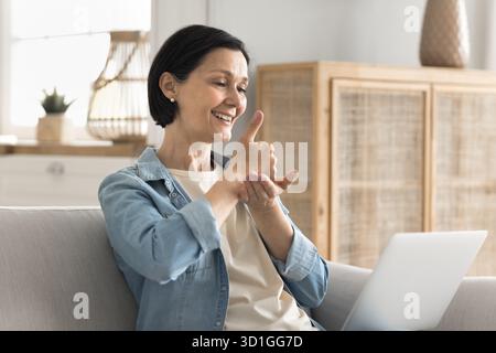 Senior woman communicating by videocall via notebook using sign language Stock Photo