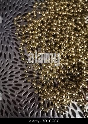 Glossy golden bead garland on textured silver background Stock Photo