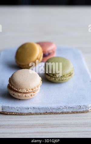 colourful French macarons in pistachio green, raspberry pink, lemon yellow, and vanilla beige shades. Stock Photo