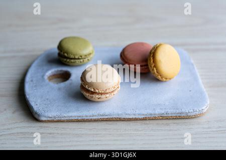 colourful French macarons in pistachio green, raspberry pink, lemon yellow, and vanilla beige shades. Stock Photo