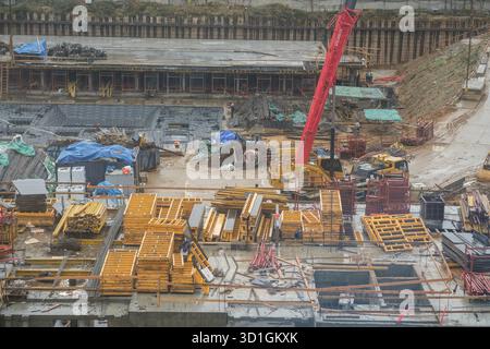 Construction Site Bustling With Activity, Featuring Cranes and Stacked Materials During an Overcast Day in an Urban Area Stock Photo