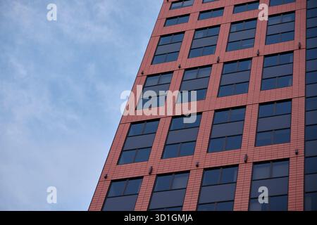 Modern red office building with glass windows against blue sky Stock Photo