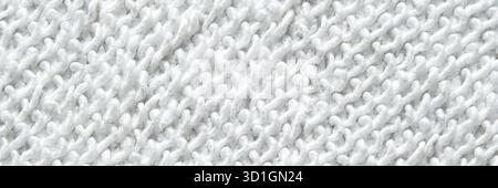 Close-up texture of white knitted fabric with intricate patterns and soft fibers visible. Stock Photo