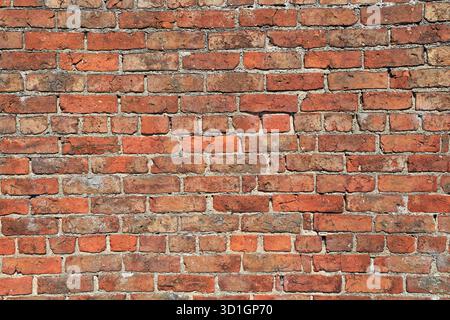 Grungy old red brick wall background with signs of deterioration Stock Photo