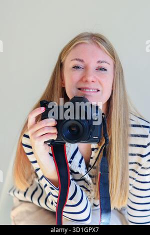 Photography blog or workshop promo with smiling woman holding camera and pointing upward. Stock Photo