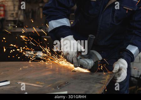 A man is diligently grinding a piece of metal using a powerful grinder, showcasing the art of metalworking in a bluecollar environment Stock Photo