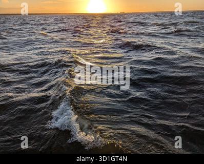 A stunningly beautiful sunset gracefully illuminating the calm ocean waves, creating an incredibly peaceful atmosphere Stock Photo