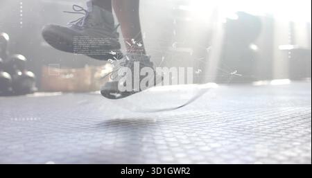 Skipping athletic male jumping over rope on rubber gym floor, with digital overlay graphics Stock Photo