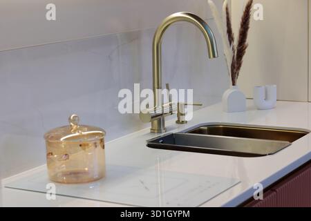 Kitchen counter with sink and built-in induction cooktop. Selective focus. Stock Photo