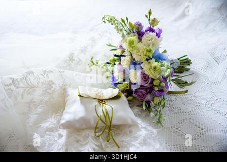 Cushion with wedding rings next to a bouquet Stock Photo