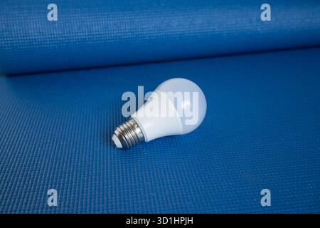 Energy-saving LED light bulb on a textured blue background, representing efficiency and modern technology. Stock Photo