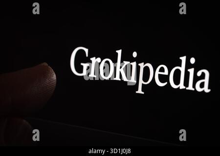 Grokipedia on laptop screen with fingertip touching the display. New platform from xAI aimed to compete with Wikipedia. Stafford, United Kingdom, Octo Stock Photo