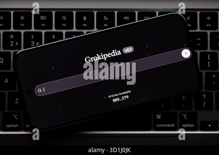 Grokipedia v0.1 search screen on phone resting across laptop keyboard, angled layout showing command and option keys. Stafford, United Kingdom, Octobe Stock Photo