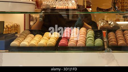 Assorted macarons in pastel colors are beautifully arranged in a pastry shop, highlighting their delicate textures and inviting presentation for desse Stock Photo