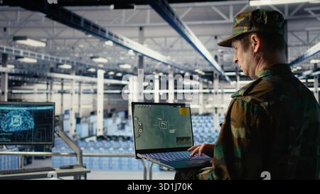 Army specialist in data center integrating AI into radar systems for missile tracking. Military soldier in server room analyzing aerial movement through artificial intelligence systems, camera A Stock Photo