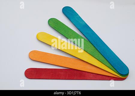 Wooden craft sticks in rainbow colors creating a fan shape pattern on a clean white background, representing creativity Stock Photo