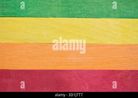 Wooden planks arranged horizontally, displaying vibrant green, yellow, orange, and red colors. Providing a dynamic abstract backdrop Stock Photo