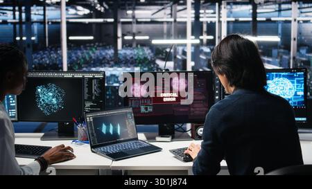 Team of engineers in data center struggles with malfunctions while using AI tools. Frustrated teamworking server hub colleagues try to fix system errors while using artificial intelligence, camera A Stock Photo