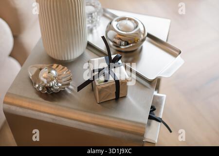 Overhead view of a wrapped Christmas gift on a coffee tablet assorted silver accessories and candles Stock Photo