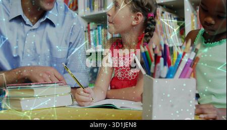 Guiding teacher leaning over textbooks with two girls at library table, with colored pencils Stock Photo