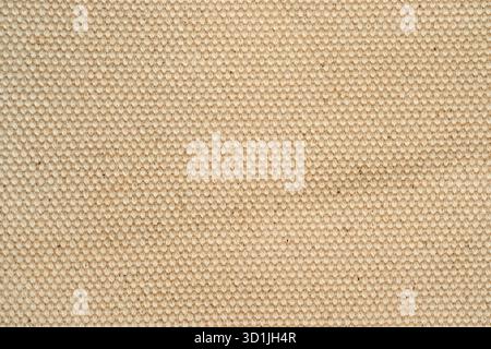 Close-up view of a woven fabric with a soft beige color. The texture shows even stitch patterns, creating a unique visual appeal. This fabric can be u Stock Photo