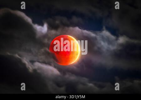 Total lunar eclipse immersed in clouds. Image captured from Costa da Caparica in Portugal. Stock Photo