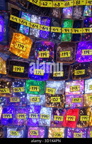 Colorful display of decorative LED string lights for sale with yellow price tags in a market stall Stock Photo
