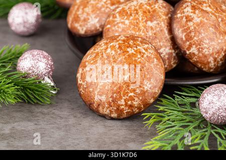 Ginger cookies on the plate, Christmas pink balls and fir-tree branches on gray background. Stock Photo