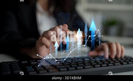 A businesswoman analyzing digital financial trends over a keyboard. The image captures the essence of growth and strategic planning in a professional Stock Photo
