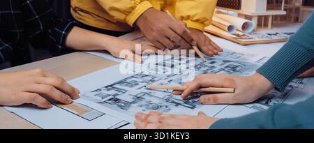 A vibrant scene depicting a collaborative design session where team members engage in planning an architectural project using blueprints and sketches Stock Photo