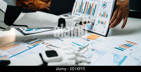A futuristic robot assistant is engaging in data analysis, showcasing various charts and graphs in a modern office setting, highlighting technology Stock Photo