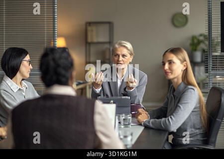 Senior Caucasian Woman Leading Business Meeting with Diverse Female Colleagues Stock Photo