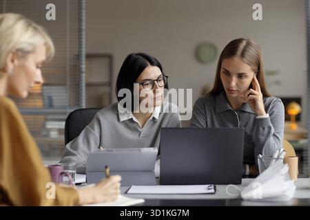 Two Young Adult Caucasian Women Collaborating on Project Using Laptop Computer Stock Photo