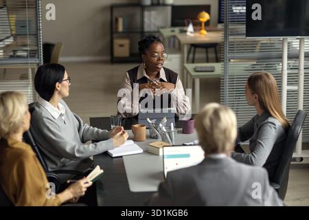 Young Black Woman Leading Business Meeting with Diverse Colleagues Collaborating Stock Photo