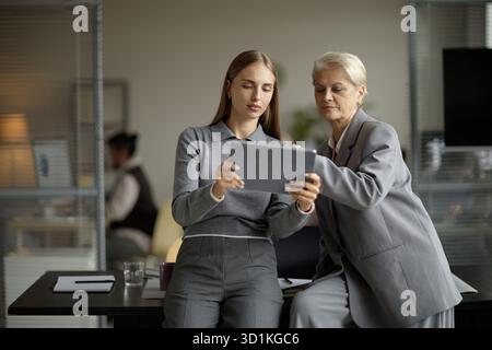 Caucasian Young Adult Woman and Senior Woman Collaborating Using Digital Tablet Stock Photo