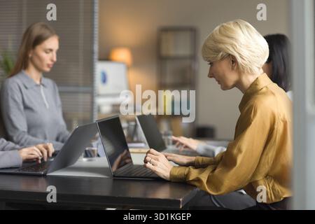 Caucasian Middle Aged Woman Collaborating with Colleagues in Modern Office Stock Photo