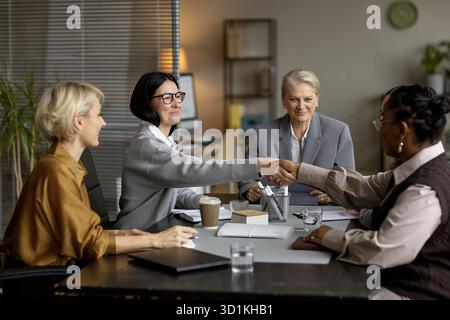 Middle Aged Multiethnic Businesswomen Shaking Hands during Office Meeting Stock Photo